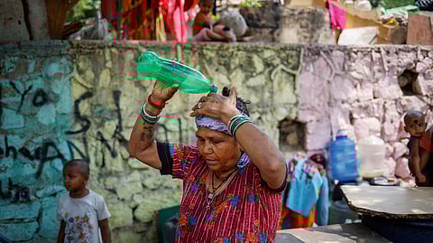 FILE PHOTO: A woman pours water on her head after filling her containers with drinking water from a municipal tanker on a hot summer day in New Delhi, India, May 21, 2024. 