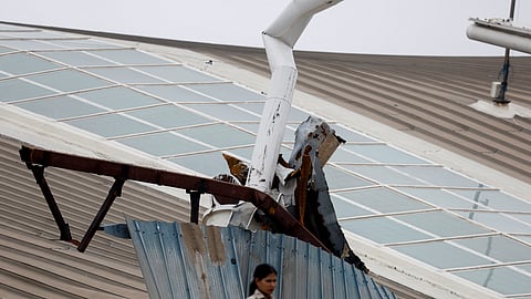 A woman stands in front of the portion of a damaged canopy at terminal 1 following heavy rainfall at the Indira Gandhi International Airport in New Delhi, India June 28, 2024. 