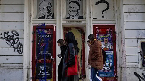 People walk past stencils depicting the last two presidents, Traian Basescu and Klaus Iohannis, with a question mark in the spot for the future president, in Bucharest, Romania, November 27, 2024. 