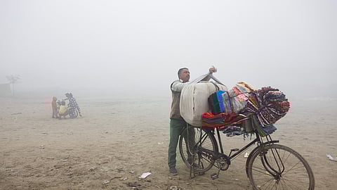 A vendor selling bedsheets loads them onto his bicycle on a foggy and cold winter morning in New Delhi, India, January 15, 2025. 