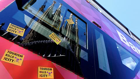 FILE PHOTO: Stickers that read "Tourism kills the City" are stuck on a Tourist City Sightseeing bus, with the La Sagrada Familia Basilica reflected on it, during a protest against mass tourism in Barcelona, Spain April 27, 2025. 