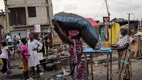 FILE PHOTO: A woman carries sack of charcoal, as she walks down a busy street, in Jamestown in Accra, Ghana December 6, 2024. 
