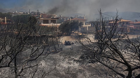A destroyed car is seen on scorched land as a wildfire burns, in the village of Thymari, near Athens, Greece, June 26, 2025. 