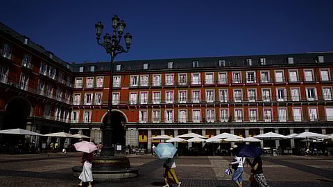 FILE PHOTO: Tourists cover themselves with umbrellas while visiting Plaza Mayor square during a heatwave in Madrid, Spain, August 4, 2025. 