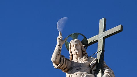 The moon appears in the sky behind the Christ the Redeemer statue on the facade of St. Peter's Basilica, on the day of a general audience in St. Peter's Square at the Vatican, November 12, 2025. 