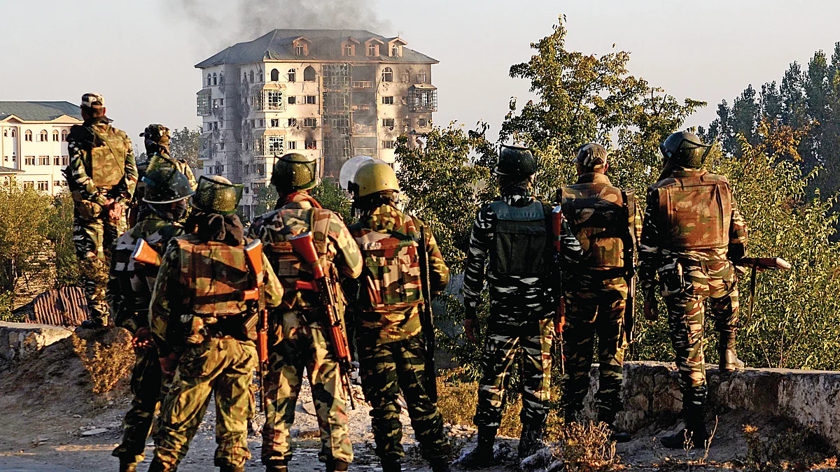 Soldiers look towards smoke billowing from a building where suspected militants had taken refuge during a gun battle in Pampore, on the outskirts of Srinagar 