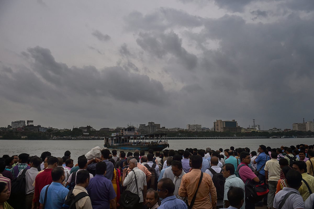 Office goers wait for a ferry to travel across a river during rainfall in Kolkata (PTI)