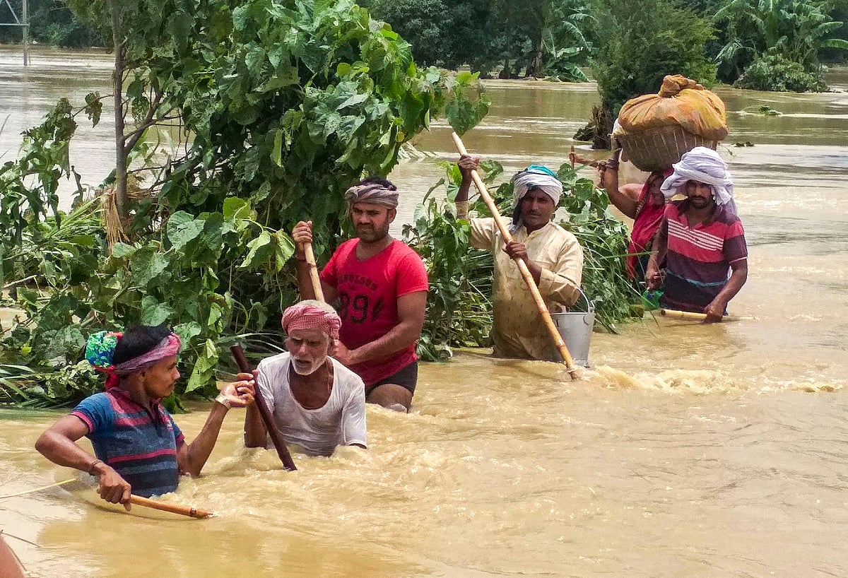  People cross a flooded street following incessant monsoon rainfall, at Madhubani district, Bihar