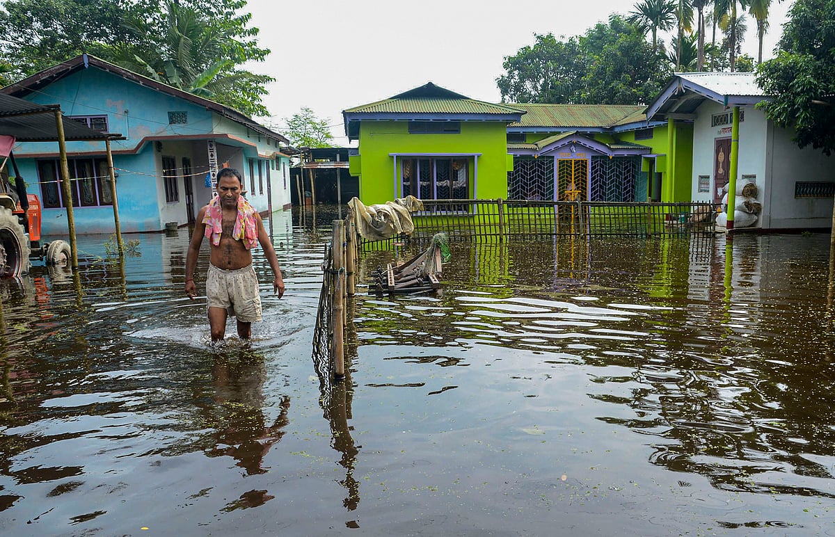 A villager leaves his house submerged in knee-deep floodwater following incessant monsoon rainfall, in Kamrup