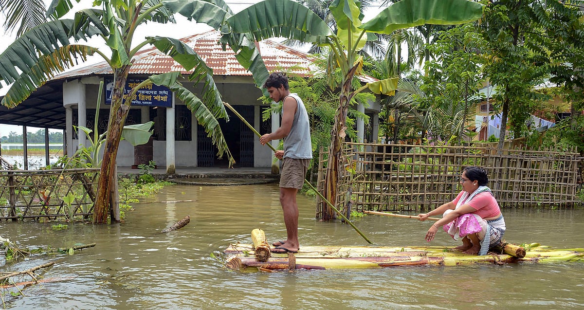 A woman arrives to offer prayers at Naamghar (temple) on a banana raft at a flood-affected Kulhiti village, in Kamrup