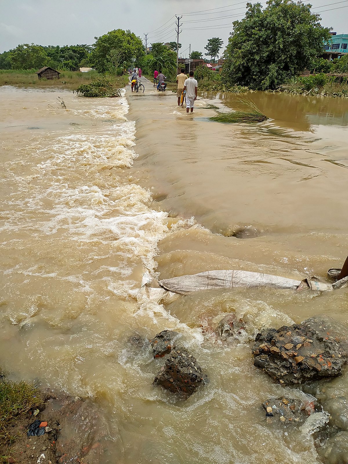 Villagers navigate through a flooded area, in Raxaul under East Champaran district of Bihar