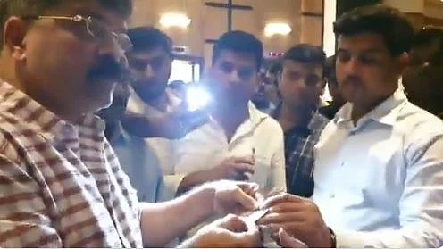 NCP MLA Jitendra Awhad (left) checking the ID cards of policemen in plainclothes at Mumbai’s Renaissance hotel where 49 of NCP legislators are lodged, on Sunday, Nov 24.