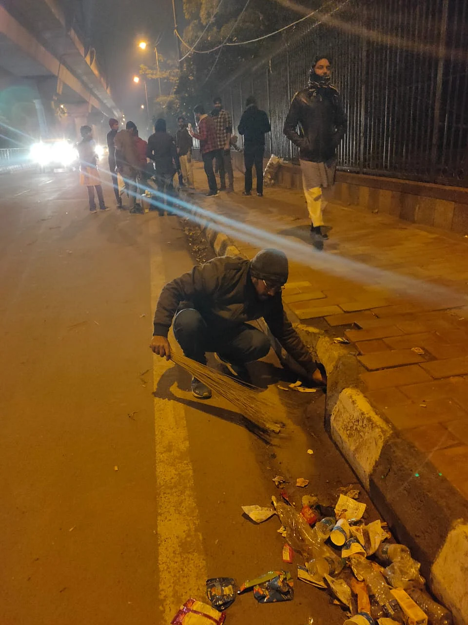 A student picking up trash at the protest site outside Jamia Millia to dump it in the dustbin. (Photo courtesy: Social media)