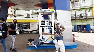 A man wearing PM Modi's mask gives a celebratory pose of a batsman as petrol & diesel prices breach Rs 100/l mark
