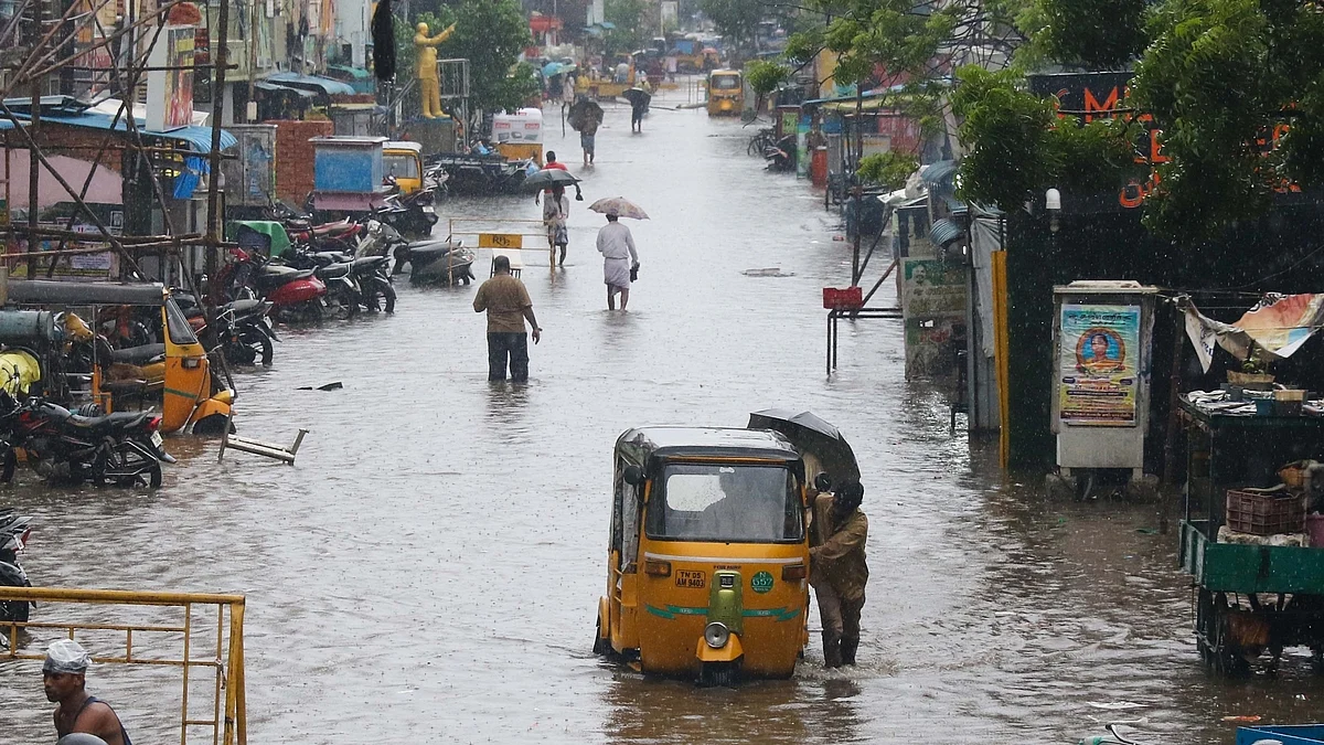 Commuters wade through flooded road during heavy rains in Chennai.