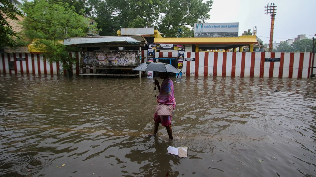 A woman holding an umbrella wades through a waterlogged road after heavy rain in Chennai.