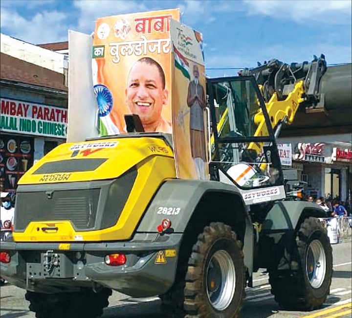 Bulldozer at a Gujarat election rally, coincidentally marigold-yellow, carrying an image of Yogi Adityanath with the legend 'Baba ka Bulldozer'