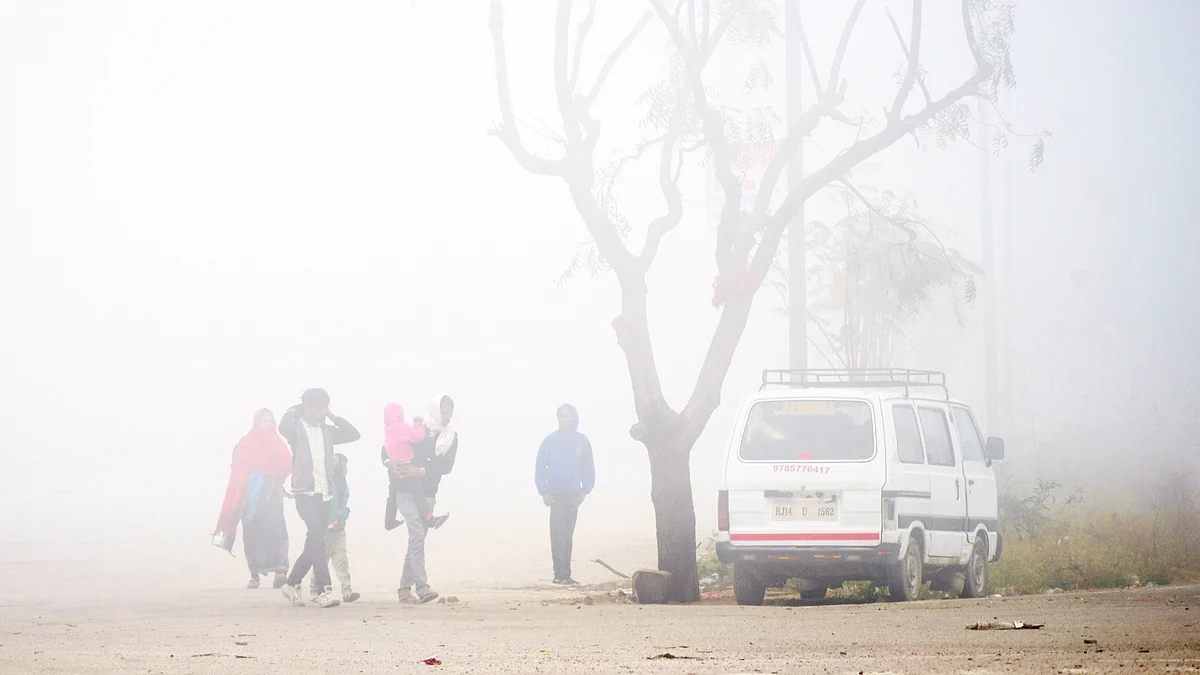 People walk past amid dense fog covering the area on a cold winter day, in Jaipur. (Photo: IANS/Ravishankar Vyas)