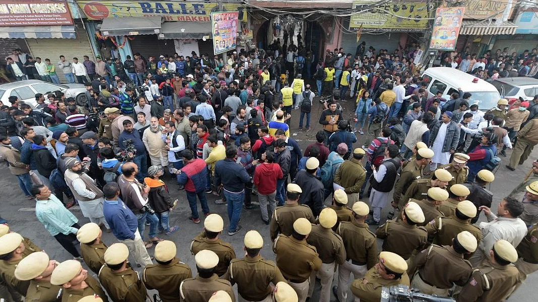 Police personnel and onlookers stand near the factory where a major fire broke out on Sunday morning, December 8, 2019. Photo: PTI/Vijay Verma