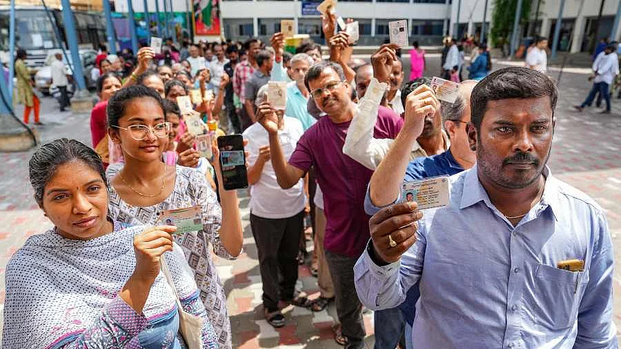 People wait in queues at a polling station to cast their votes for Karnataka Assembly elections, in Bengaluru. (Photo Courtesy: PTI)