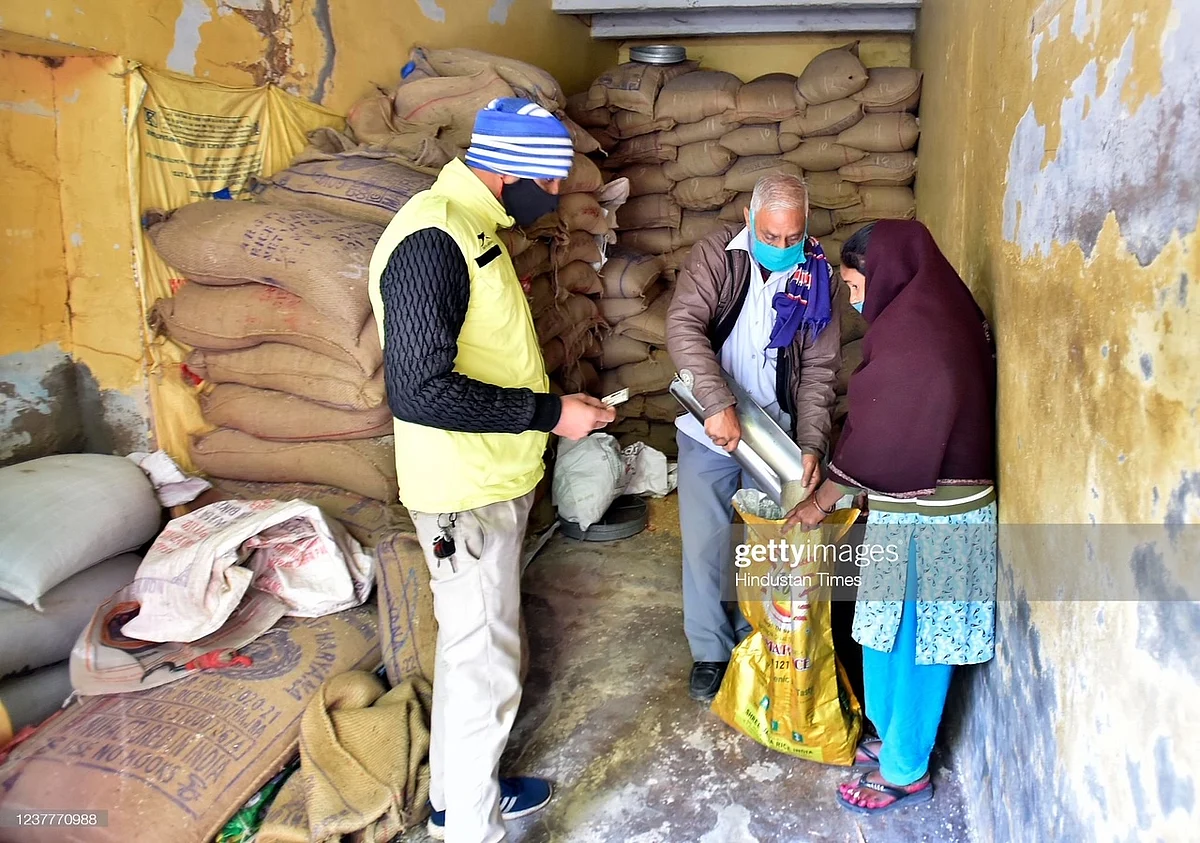 A woman at a rice godown where a man fills the sack she is holding at a Delhi government ration shop in Khichripur (photo: Raj K Raj/Hindustan Times via Getty Images)