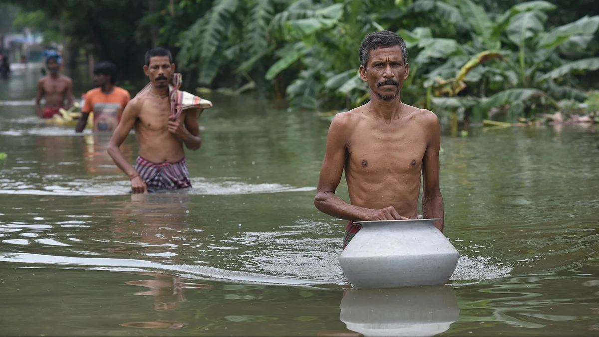 Villagers wade through flood water as the village is severely hit by a flood. (Photo by Sukhomoy Sen/NurPhoto via Getty Images)