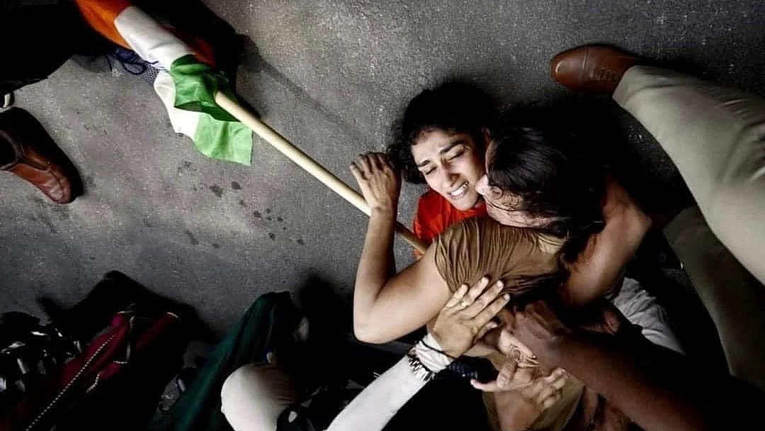 Vinesh Phogat and Sangeeta Phogat being held down by the police in a crackdown of their month-long protest as they attempted to march to the new parliament in New Delhi, on Sunday, May 28. (Photo: @cpimcc/Instagram)