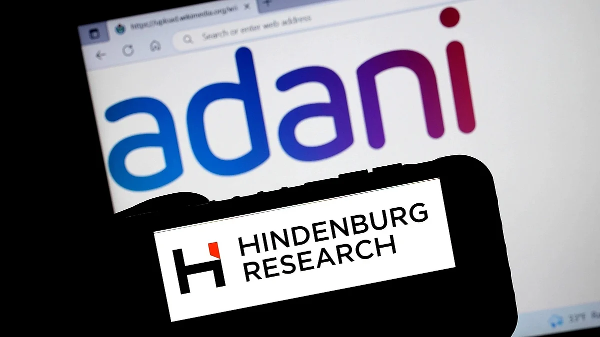 Representative image of Adani logo on a computer screen with a second device carrying a Hindenburg Research label pointed at the screen (artwork: National Herald)