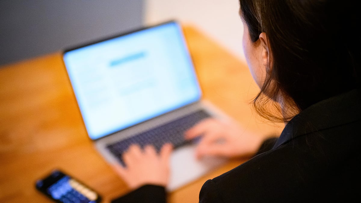 A woman sits at her laptop.