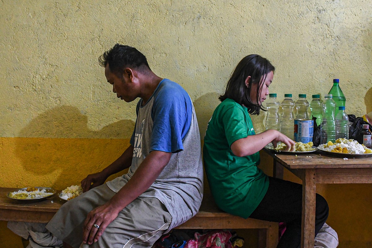 Churachandpur, Manipur: Jamkhothang Baite (L) eats lunch with his daughter at a relief camp in Rengkia village (photo: Getty Images)