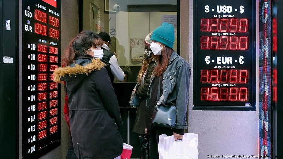 Two people standing in front of a currency display board (photo: DW)