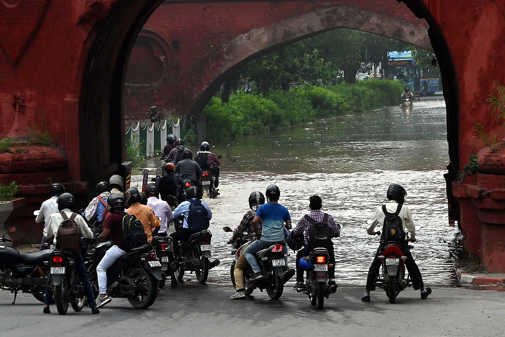 Waiting motorcyclists on a flooded street in New Delhi (Photo: Getty Images)