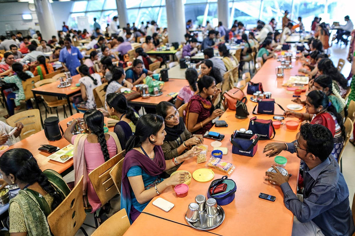 Employees dine in a canteen at the Tata Consultancy Services Ltd. (TCS) campus in Chennai, India. Many bring their own lunch, sharing, alongside those choosing the cafeteria offerings (photographer: Dhiraj Singh/Bloomberg via Getty Images)