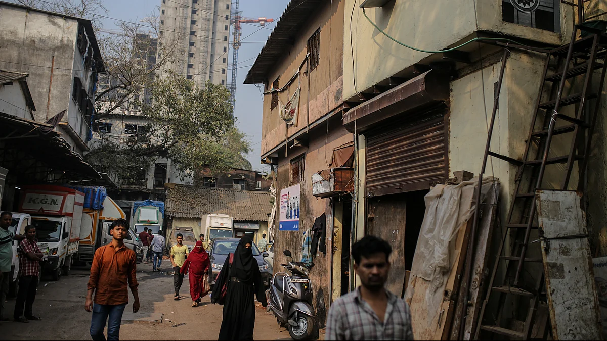 People walk on a street with a residential building under construction in the background in the Dharavi district on Jan 5, as Indian billionaire Gautam Adani plans to revamp Mumbai's famed slum (photo: Dhiraj Singh/Bloomberg via Getty Images)