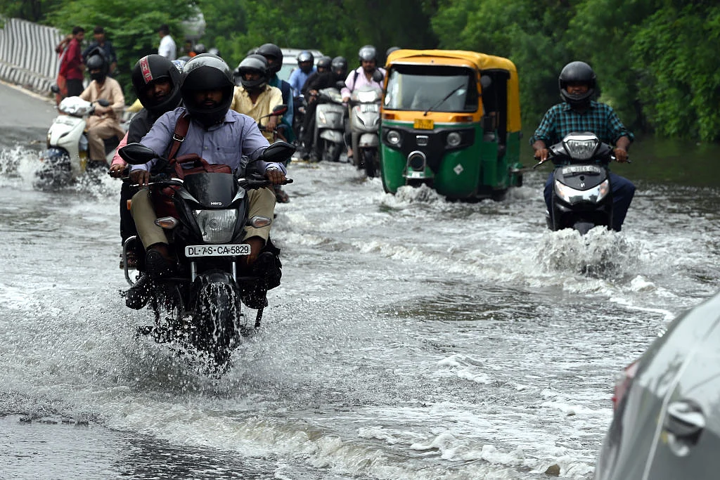 Motorcyclist drives through a flooded street in New Delhi (Photo: Getty Images)