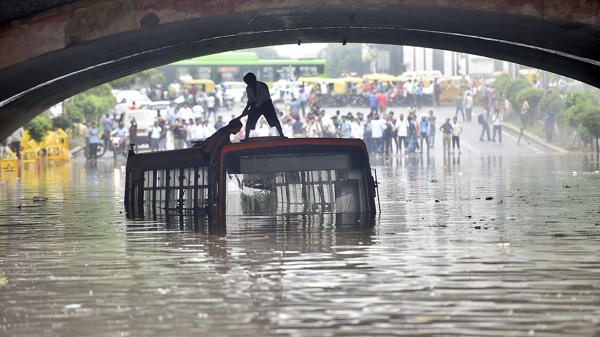 Two local boys wait for help on top of a bus after heavy rain inundated the road under the Minto Road Bridge on 16 July 2018 in New Delhi, India (photo: Getty Images)