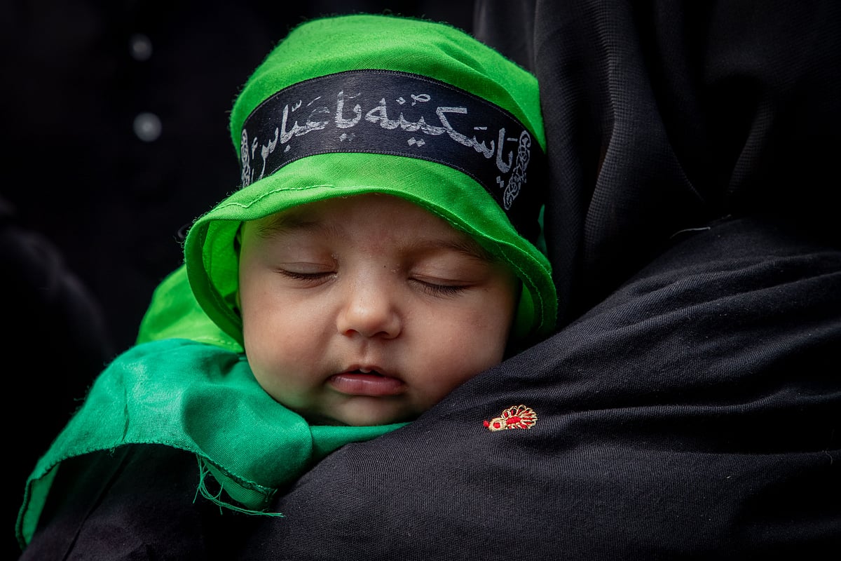 A Muslim woman carries her child in a Muharram procession on Ashura, in Srinagar, Jammu & Kashmir (photo by Faisal Bashir/SOPA Images/LightRocket via Getty Images)