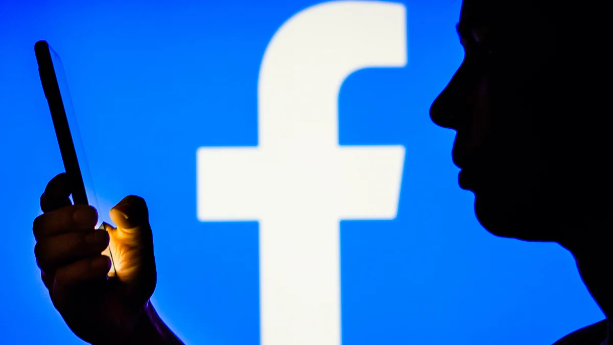 Representative image of a person using a smartphone with a Facebook logo in the backdrop (photo: Getty Images)