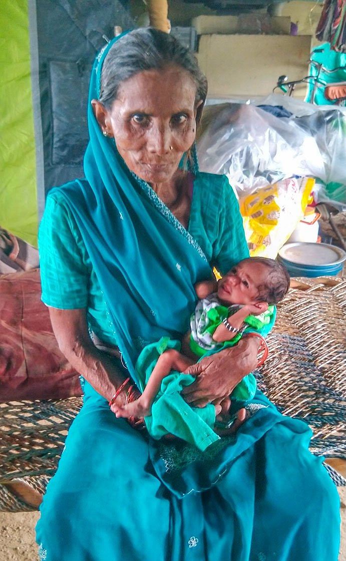 Geeta, holding her neighbour’s month-old baby, who she ran to rescue when the Yamuna water rushed into their homes near Mayur Vihar metro station in July (photo: Shalini Singh for PARI)