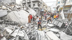 Palestinians walk among the rubble of a destroyed building, following an Israeli air attack on Khan Yunis, 10 October 2023. (Photo: Getty Images)