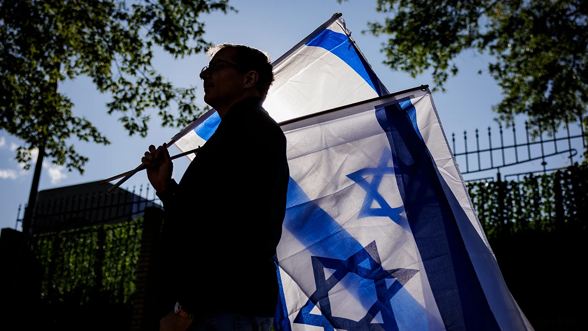 Representative image of a man carrying two Israeli flags (Photo by Samuel Corum/Getty Images)