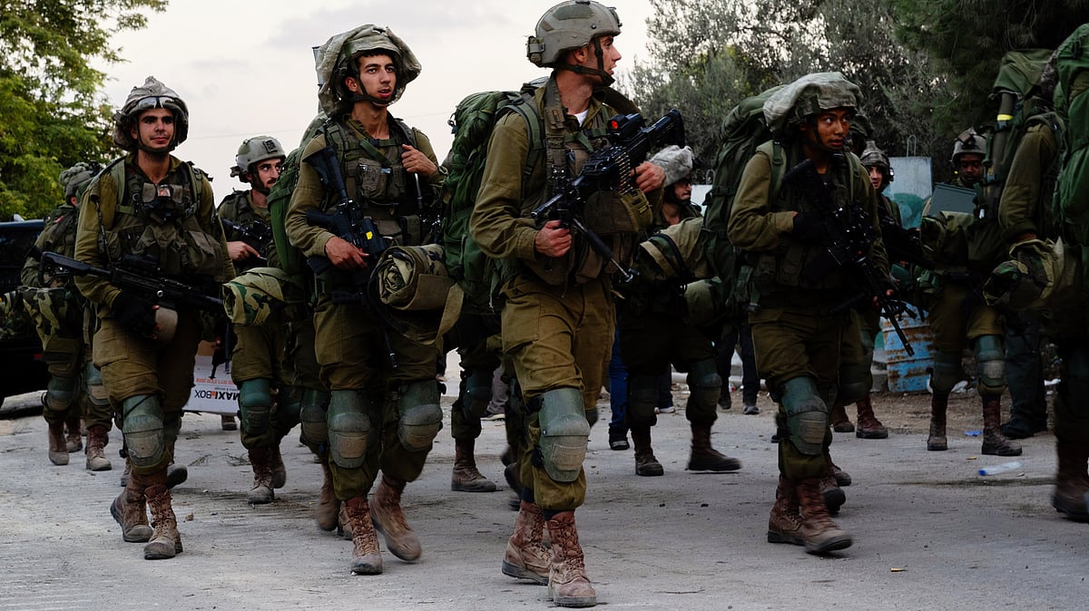 Offline and online: Israeli soldiers walk through Kibbutz Be'eri four days after the 7 October Hamas attacks near the border with Gaza (photo: Getty Images)