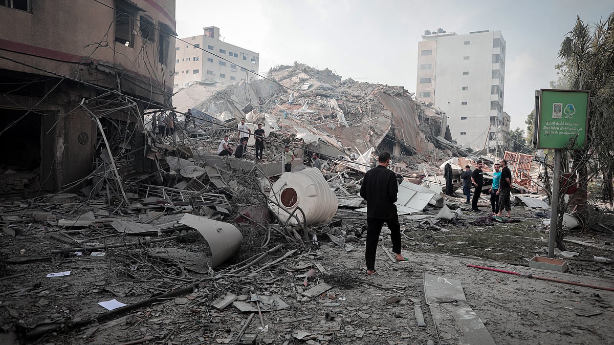 Palestinians inspect the ruins of Watan Tower destroyed in Israeli airstrikes in Gaza city, on 8 October (Photo: Momen Faiz/NurPhoto via Getty Images)