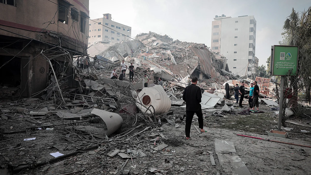 Palestinians inspect the ruins of Watan Tower destroyed in Israeli airstrikes in Gaza city, on 8 October (Photo: Momen Faiz/NurPhoto via Getty Images)