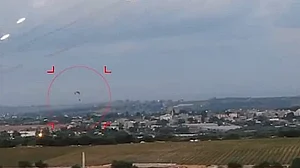 Rockets are seen shooting over a settlement in the Gaza strip while a paratrooper lands during the Hamas attack on Israel on 7 October 2023 (photo: IANS)
