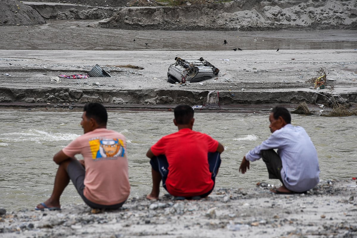Three men watch an overturned car along the Teesta (photo: Getty Images)