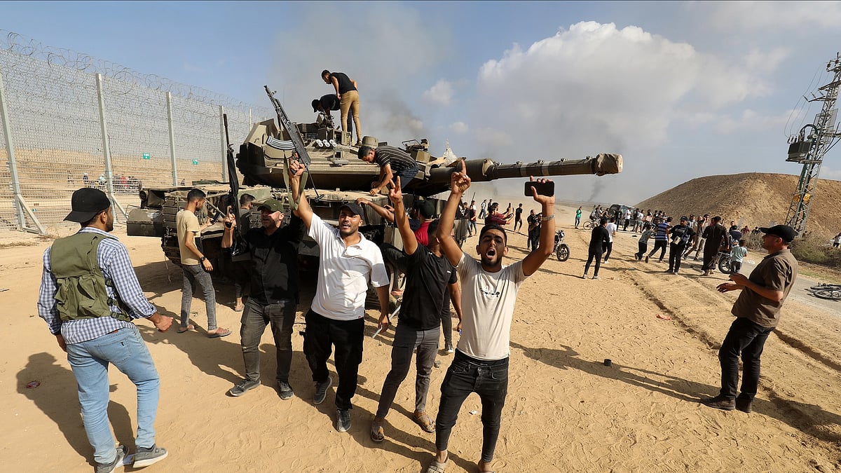 The Al-Qassam Brigades, the armed wing of the Palestinian resistance group Hamas take apart an Israeli tank as smoke rises near the Israel–Gaza border on 7 October 2023.   (Photo: Abed Rahim Khatib/Anadolu Agency via Getty Images)