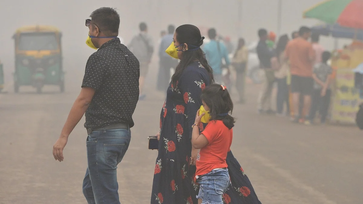 A family in Delhi with a young child walks through smog in pollution masks (photo: NH archives)