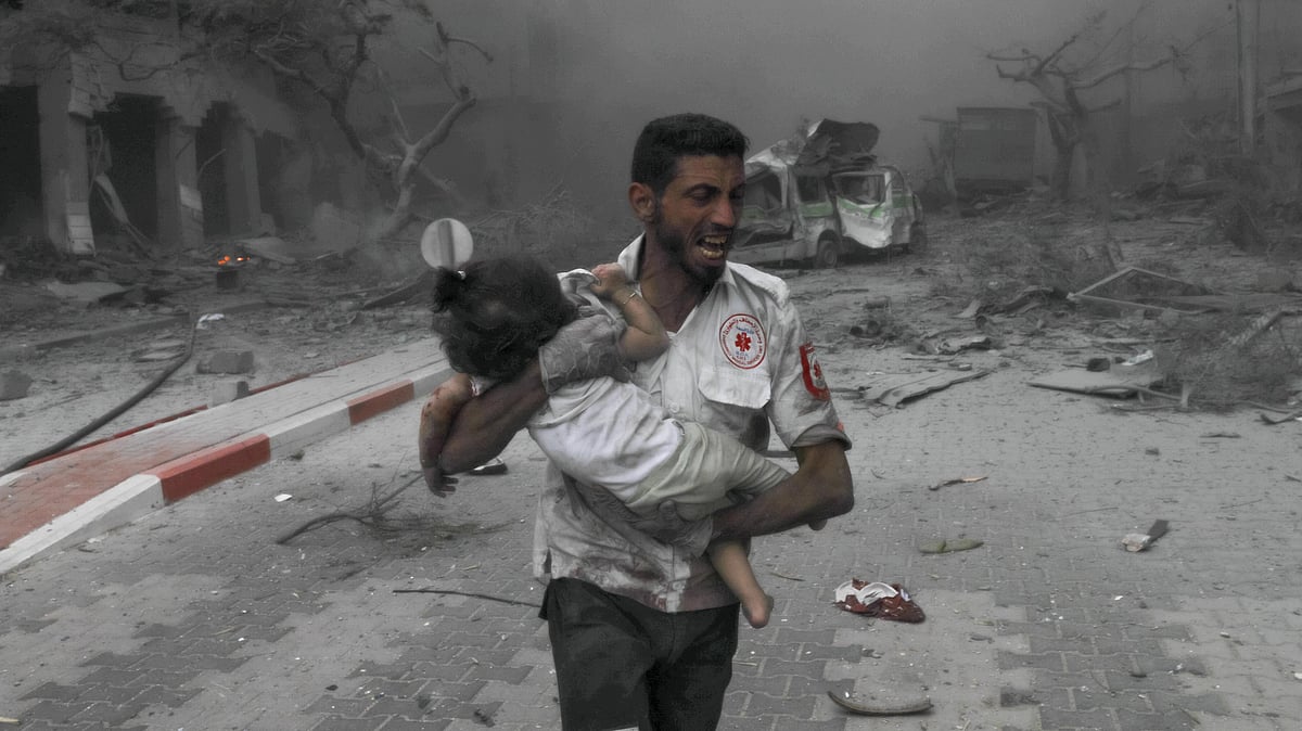 A medical worker rushes a child to an ambulance for treatment amidst Israeli airstrikes in Gaza City (photo: Getty Images)