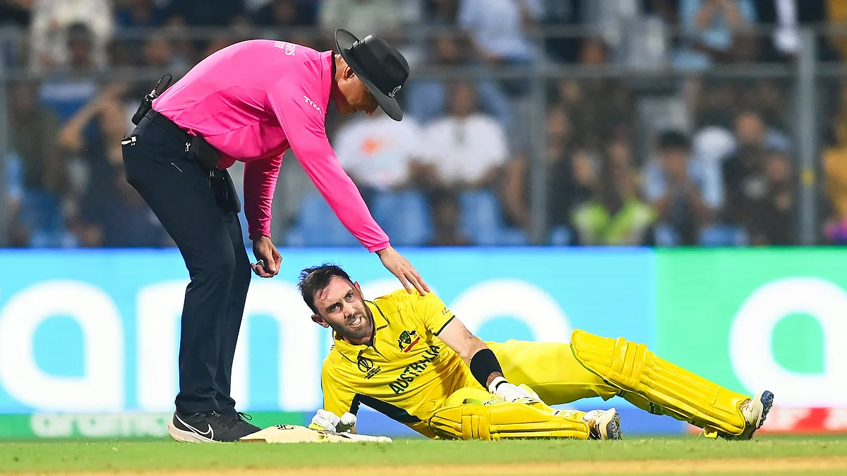 Glenn Maxwell collapses as umpire Alex Wharf tries to offer a helping hand during the World Cup 2023 Australia-Afghanistan match in Mumbai on 7 November (photo: Getty Images)